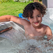 Child in a hot tub with a grassy area in the background